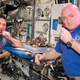Dos astronautas probando la lechuga sembrada a bordo de la Estación Espacial Internacional.